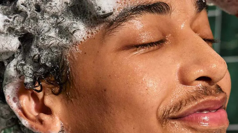 一位神情放松的男士用洗发剂洗发的特写镜头